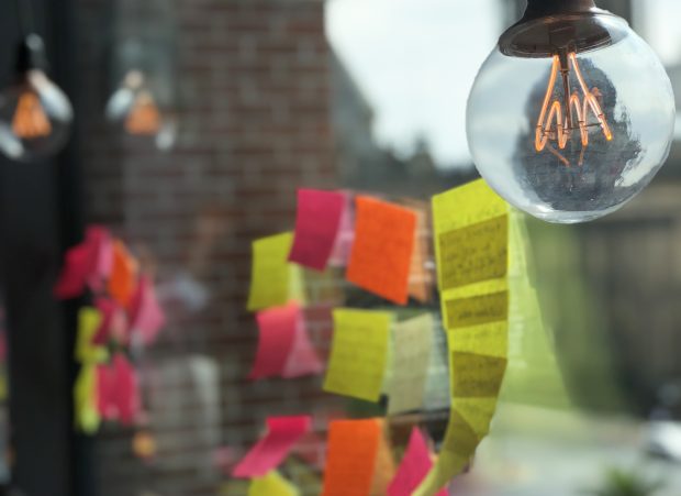 Postit notes on a window with lightbulbs hanging
