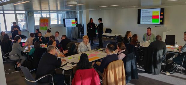 Attendees at the Developer Contributions workshop discuss around tables in a meeting room.