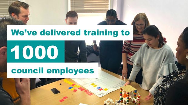 Picture of 7 council staff stood around a table building lego, with text overlayed: We've delivered training to 1000 council employees