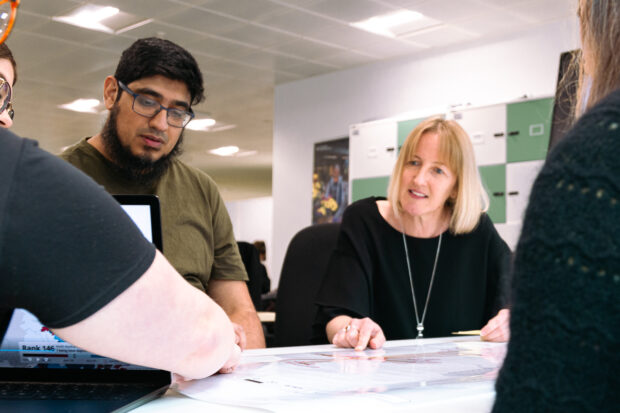 Fiona Clowes looking over a document with the team. Fiona sits next to data scientist colleagues in the office.