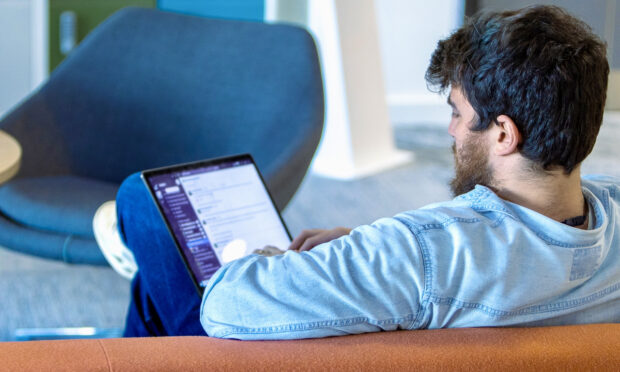 A person sitting with their back to the camera and working on a laptop
