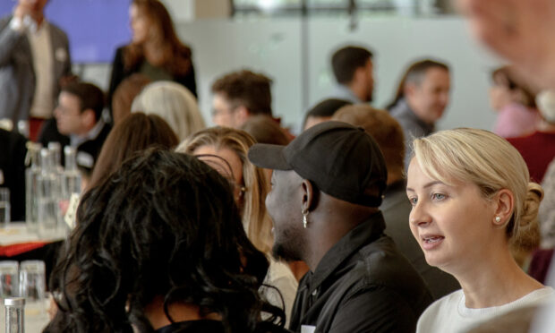 A large group of people sitting down, in a conference setting