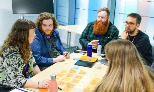 a group of people sitting around a table with some post-it notes and talking to each other 