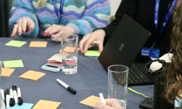 post it notes on a table, with some hands visible, arranging them