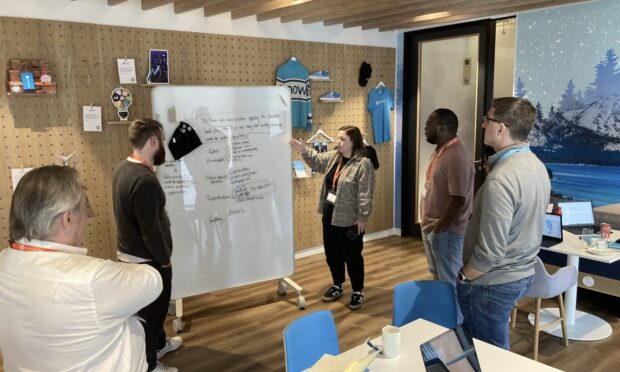 The hackathon team standing in a room looking at ideas on a white board