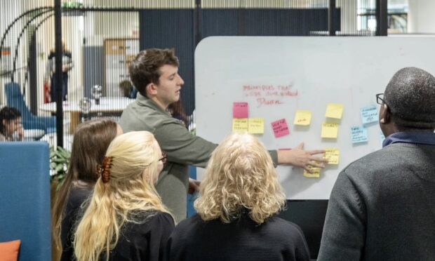 a team member presenting something on a board with post-its to the rest of the team