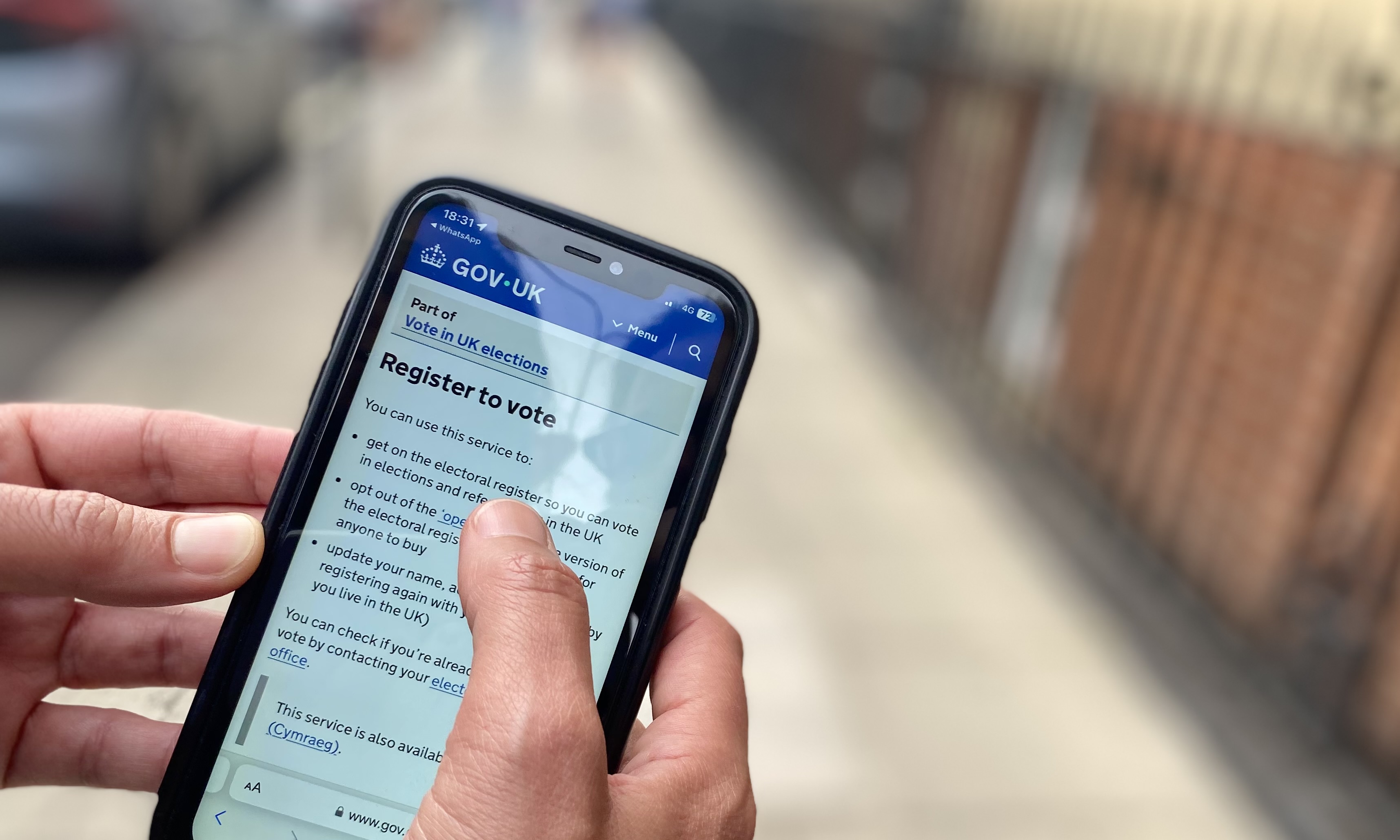 an image of someone holding a mobile phone showing the register to page on GOV.UK