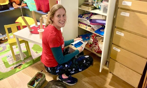 Emma Crowe sorting through items in a messy cupboard