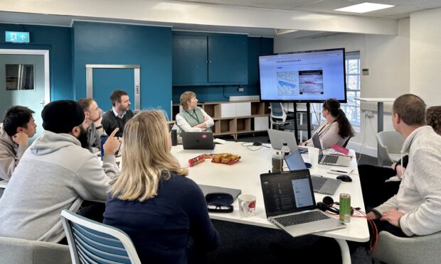 a group of people sitting around a table looking at a big screen showing the Extract tool 