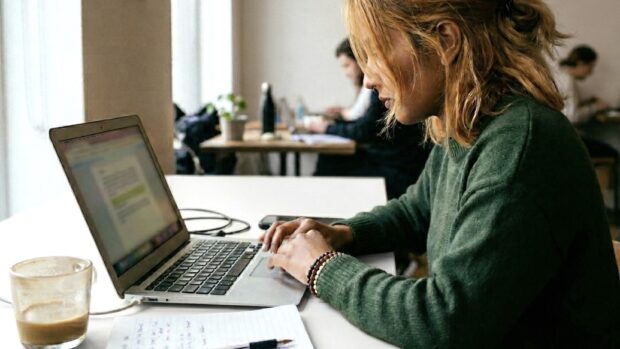 a person seen from the side, working on a laptop in an office